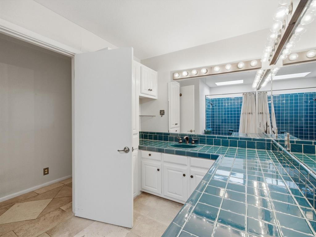 1104 Coffield Street Bowie, TX 76230 - Photo 25 of 39 a bathroom with a granite countertop sink a mirror and a shower
