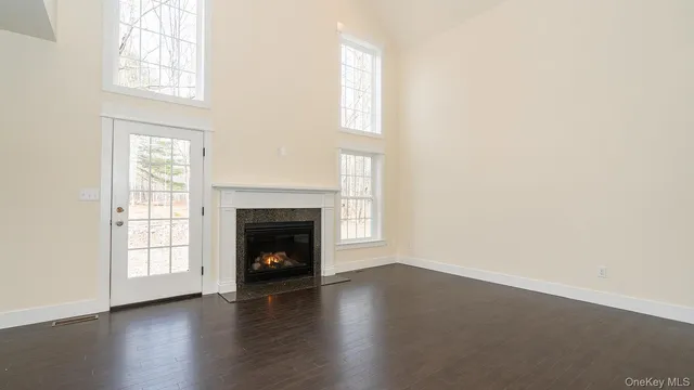 an empty room with wooden floor fireplace and windows