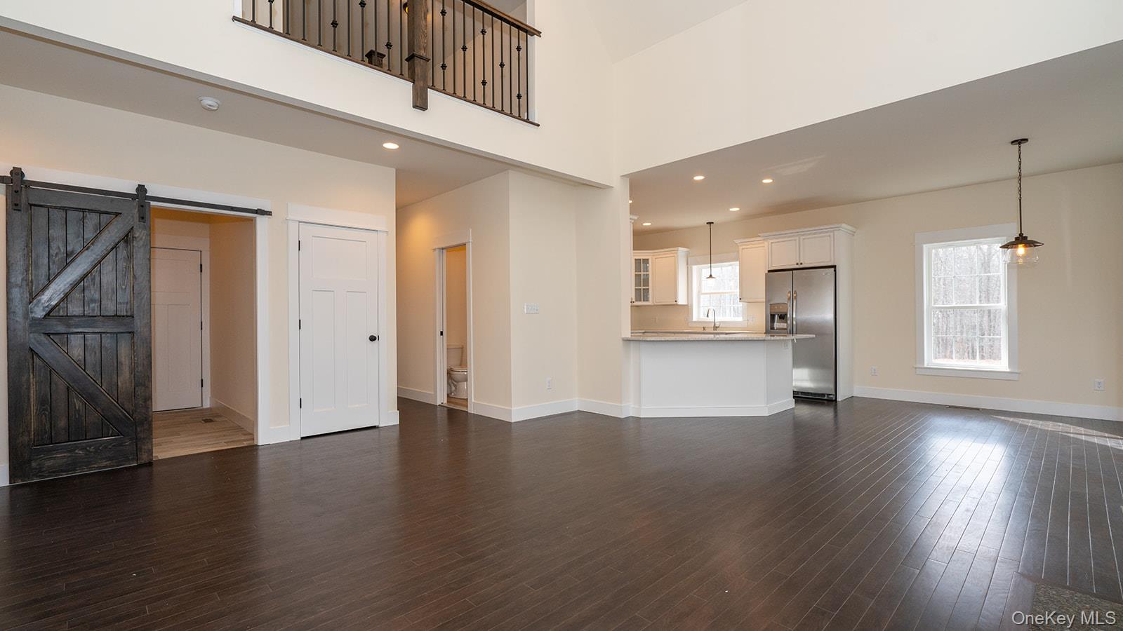 43 Malloy Road Wallkill, NY 12589 - Photo 14 of 50 Unfurnished living room with a barn door, recessed lighting, a high ceiling, and dark wood-style flooring