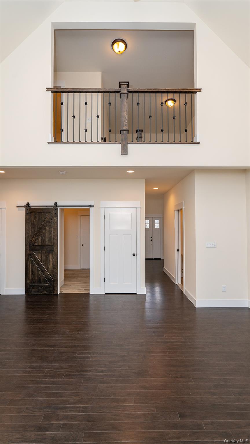 43 Malloy Road Wallkill, NY 12589 - Photo 16 of 50 Unfurnished living room featuring high vaulted ceiling, a barn door, and dark wood-style flooring