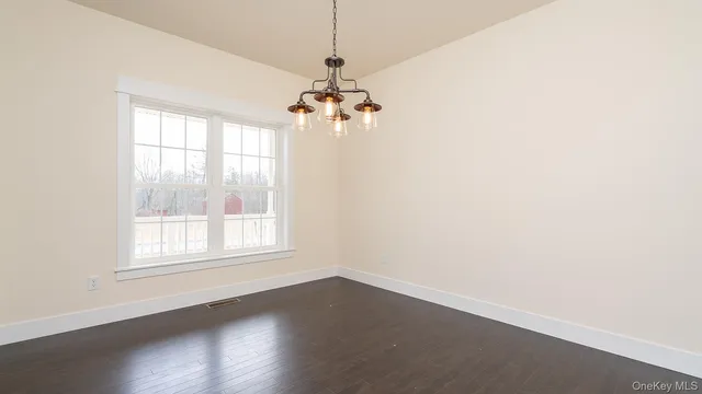 an empty room with wooden floor chandelier fan and windows