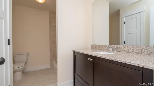 a bathroom with a granite countertop sink a toilet and a mirror