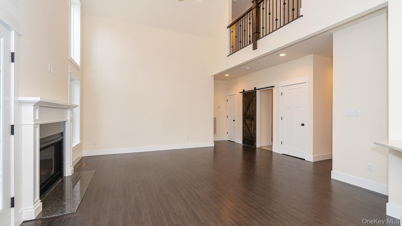 43 Malloy Road Wallkill, NY 12589 - Photo 10 of 50 Unfurnished living room with a barn door, dark wood-style floors, a towering ceiling, a fireplace, and recessed lighting