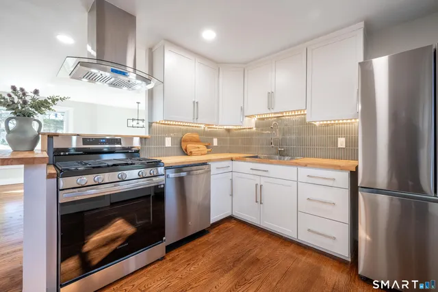 a kitchen with stainless steel appliances granite countertop a stove a refrigerator and a stove top oven