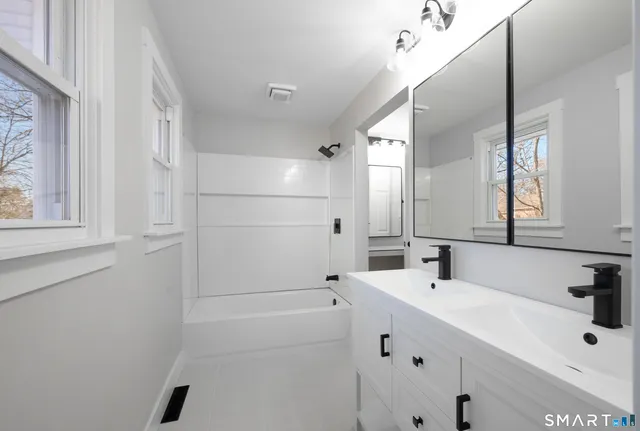 a bathroom with a tub sink and mirror