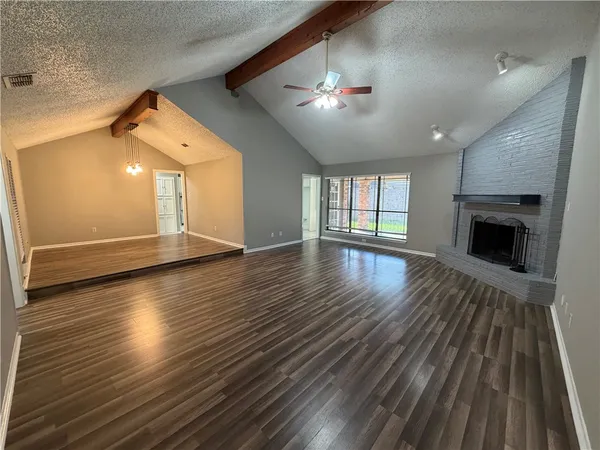 a view of an empty room with wooden floor fireplace and a window