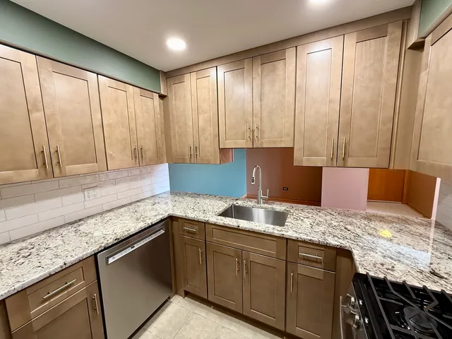 a kitchen with granite countertop a sink and a white cabinets