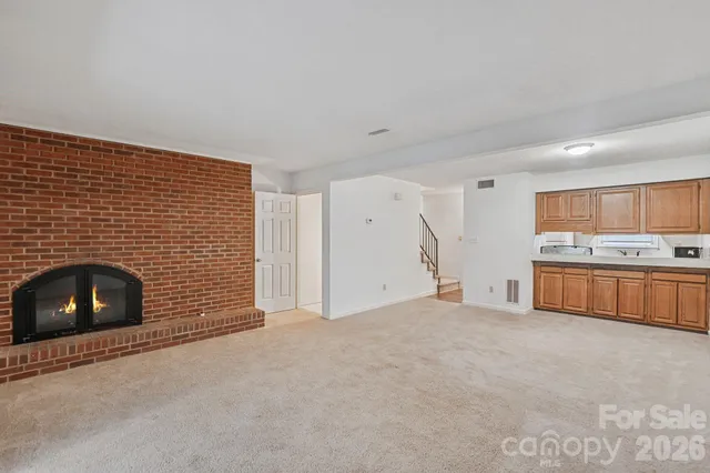 a view of an empty room with a fireplace and cabinets