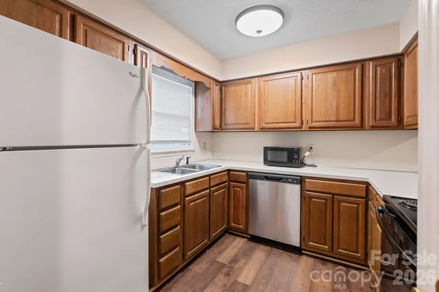 a kitchen with stainless steel appliances granite countertop a sink a stove a refrigerator with grey cabinets and wooden floor