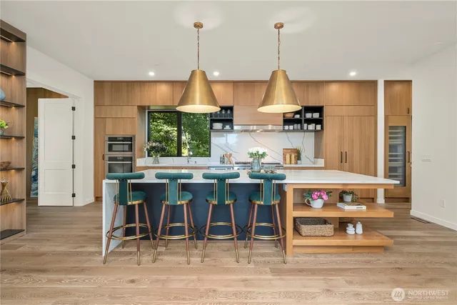 a kitchen with stainless steel appliances kitchen island granite countertop a table chairs and a wooden floor