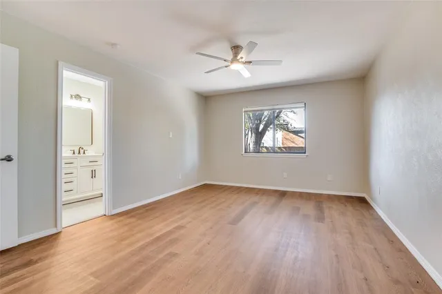 an empty room with wooden floor chandelier fan and windows