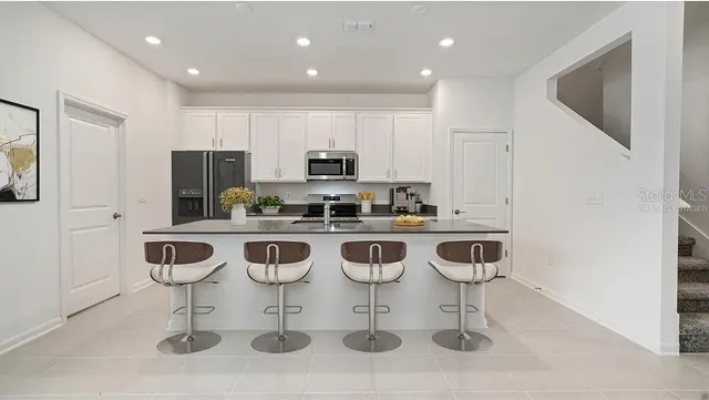 a kitchen with stainless steel appliances kitchen island a dining table and chairs
