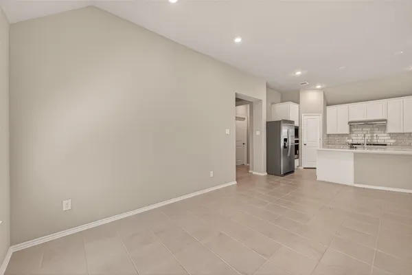a view of kitchen with refrigerator and white cabinets