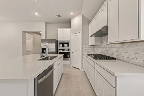 a kitchen with white cabinets appliances and sink