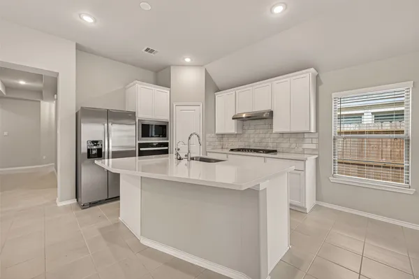 a kitchen with stainless steel appliances granite countertop a stove top oven a sink and a refrigerator