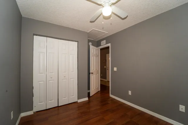 an empty room with wooden floor chandelier fan and closet area