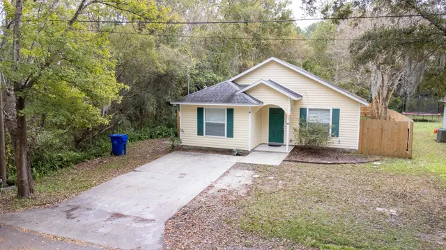 a view of a house with a yard and large tree