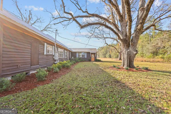 a view of a yard in front of a house with large trees