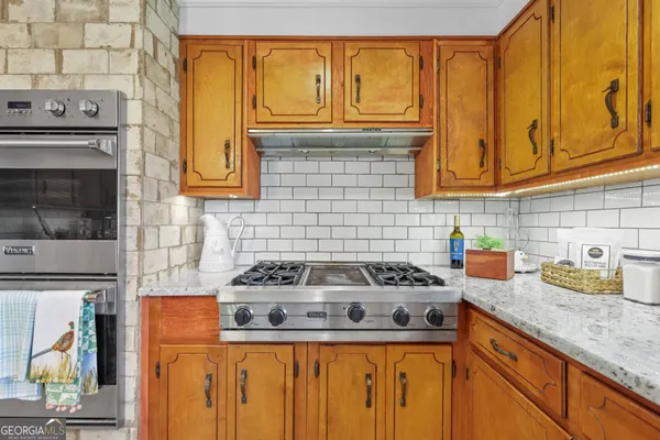 a kitchen with granite countertop cabinets and a stove top oven