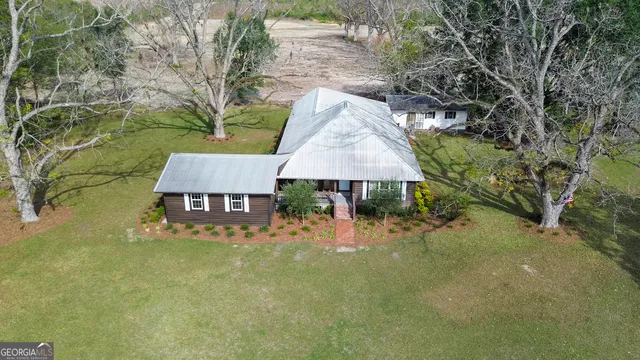 an aerial view of a house with table and chairs under an umbrella
