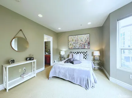 a bedroom with a bed and a large mirror on the dresser