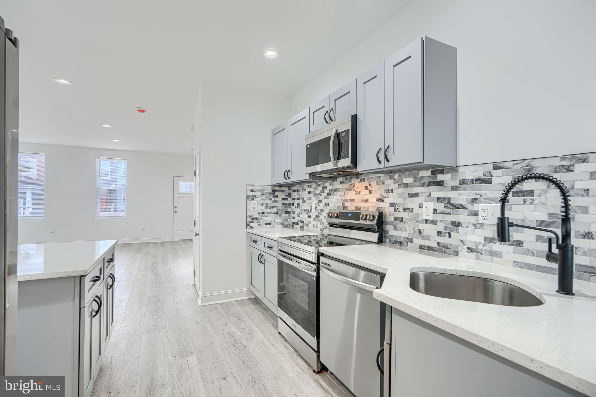 615 Linnard Street Baltimore, MD 21229 - Photo 4 of 28 a kitchen with stainless steel appliances a sink dishwasher a stove top oven a refrigerator with wooden floor