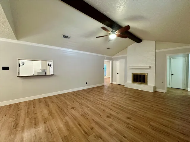 a view of empty room with wooden floor and ceiling fan