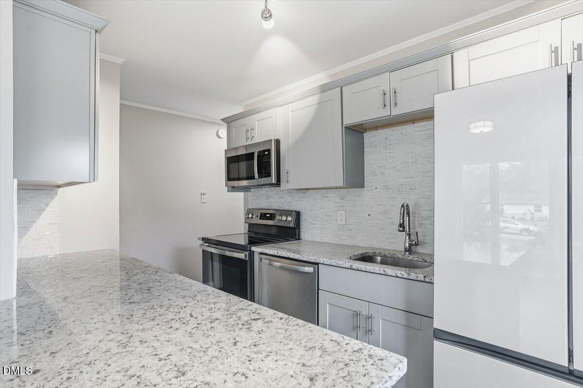 713 Friar Tuck Road Raleigh, NC 27610 - Photo 17 of 29 a kitchen with stainless steel appliances kitchen island a stove a sink and a refrigerator