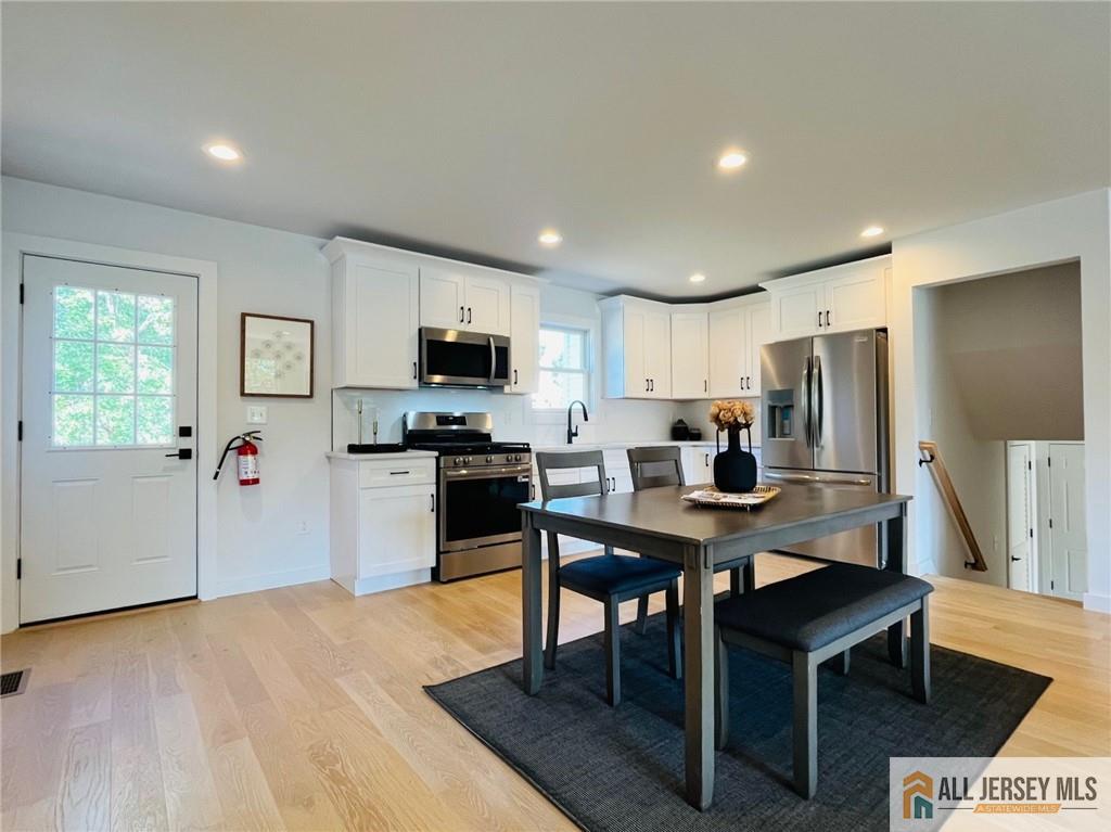 42 Larchmont Road Edison, NJ 08837 - Photo 5 of 36 a kitchen with a refrigerator a stove a microwave oven a sink dishwasher and white cabinets with wooden floor