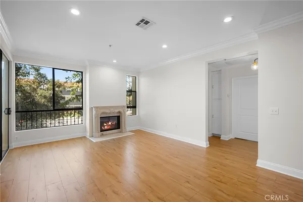 an empty room with wooden floor fireplace and windows