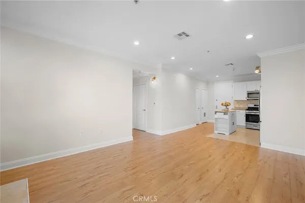 a view of a kitchen with kitchen island wooden floors wooden cabinets and living room
