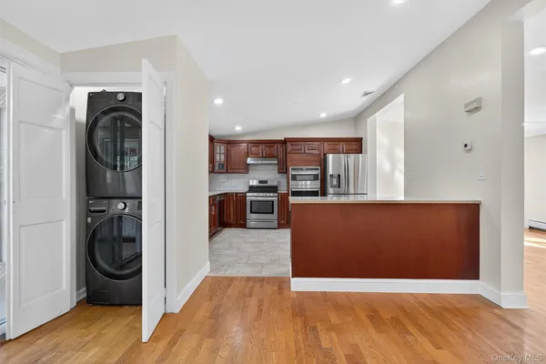 a view of a kitchen with stainless steel appliances wooden floor and chair