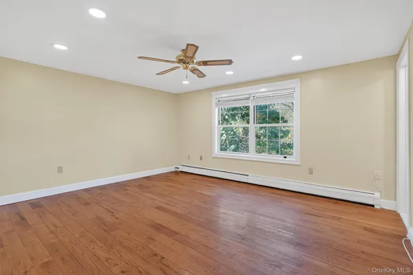 an empty room with wooden floor fan and windows