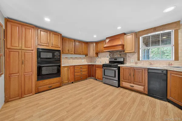 a kitchen with granite countertop wooden floors stainless steel appliances and window