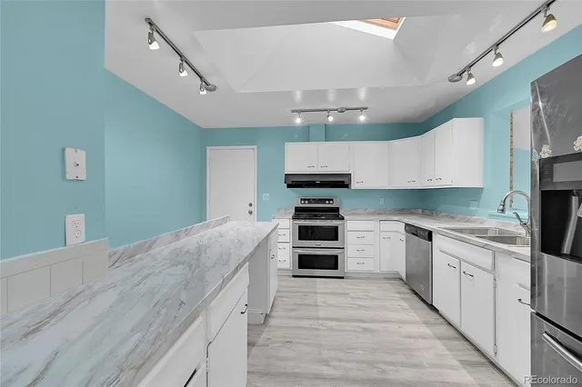 a large kitchen with stainless steel appliances kitchen island granite countertop a stove and a sink