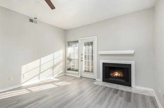 a view of an empty room with wooden floor fireplace and a window
