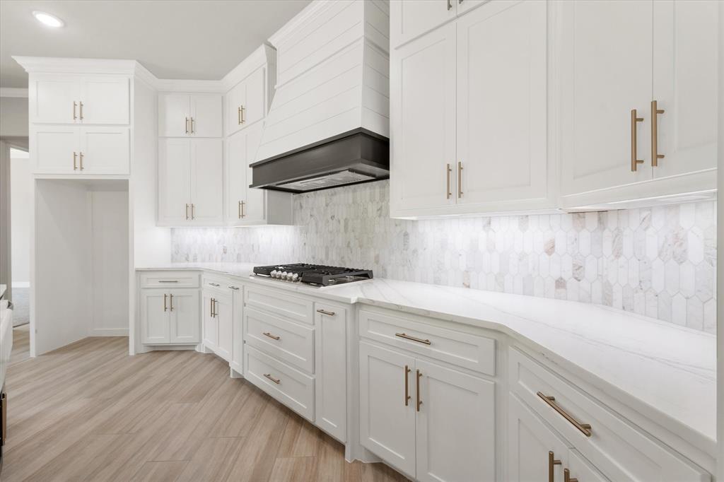 6610 Waggoner Way Midlothian, TX 76065 - Photo 10 of 40 Modern kitchen featuring white cabinetry with gold-finish hardware, a gas cooktop, and a white pick-tile backsplash