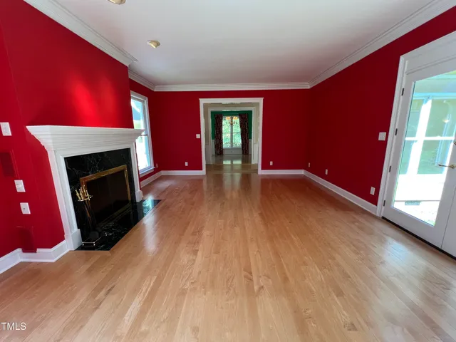 a view of an empty room with wooden floor fireplace and a window