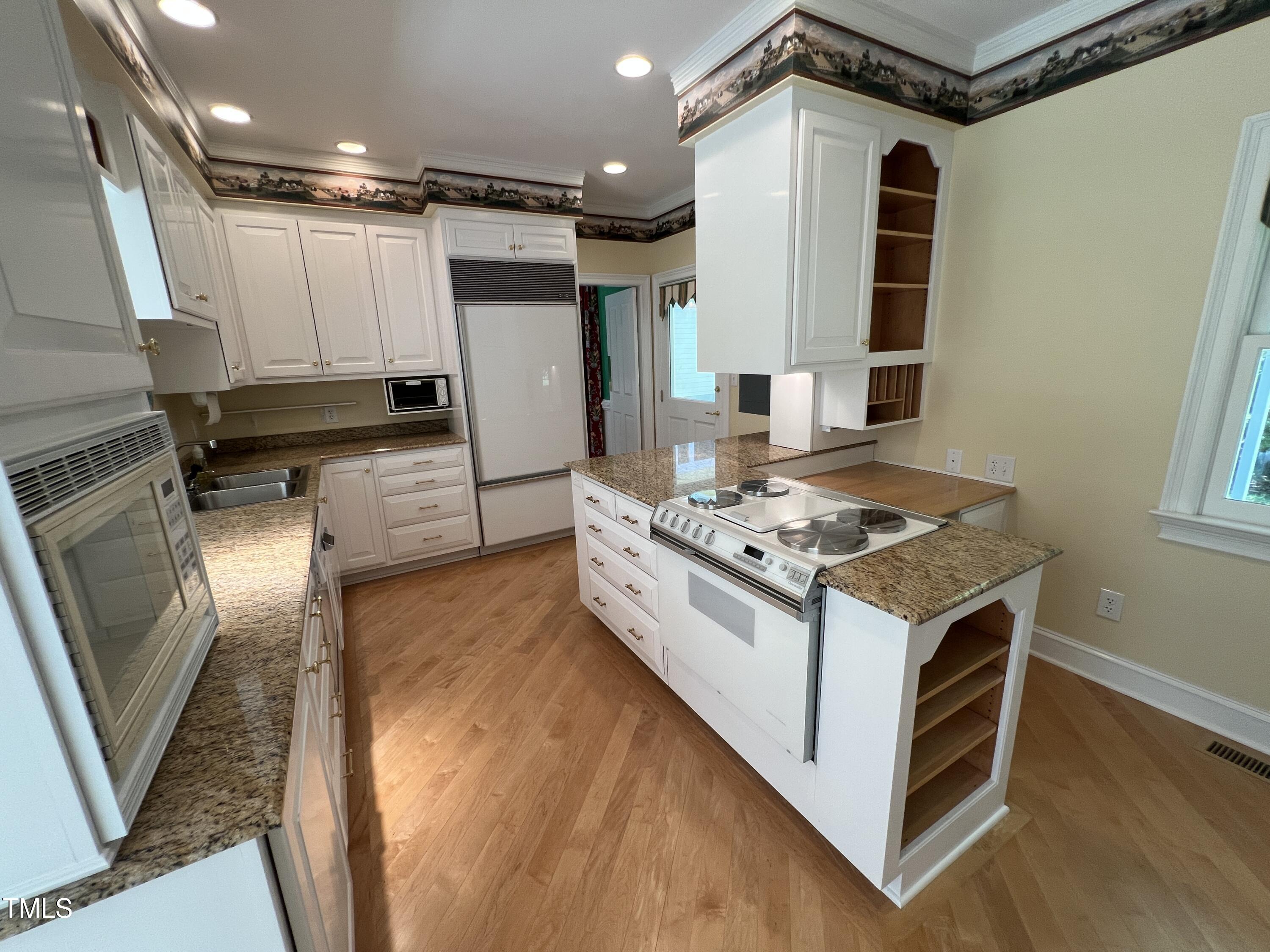 1208 Goodwin Road Apex, NC 27523 - Photo 20 of 42 a kitchen with kitchen island a stove a sink and a refrigerator
