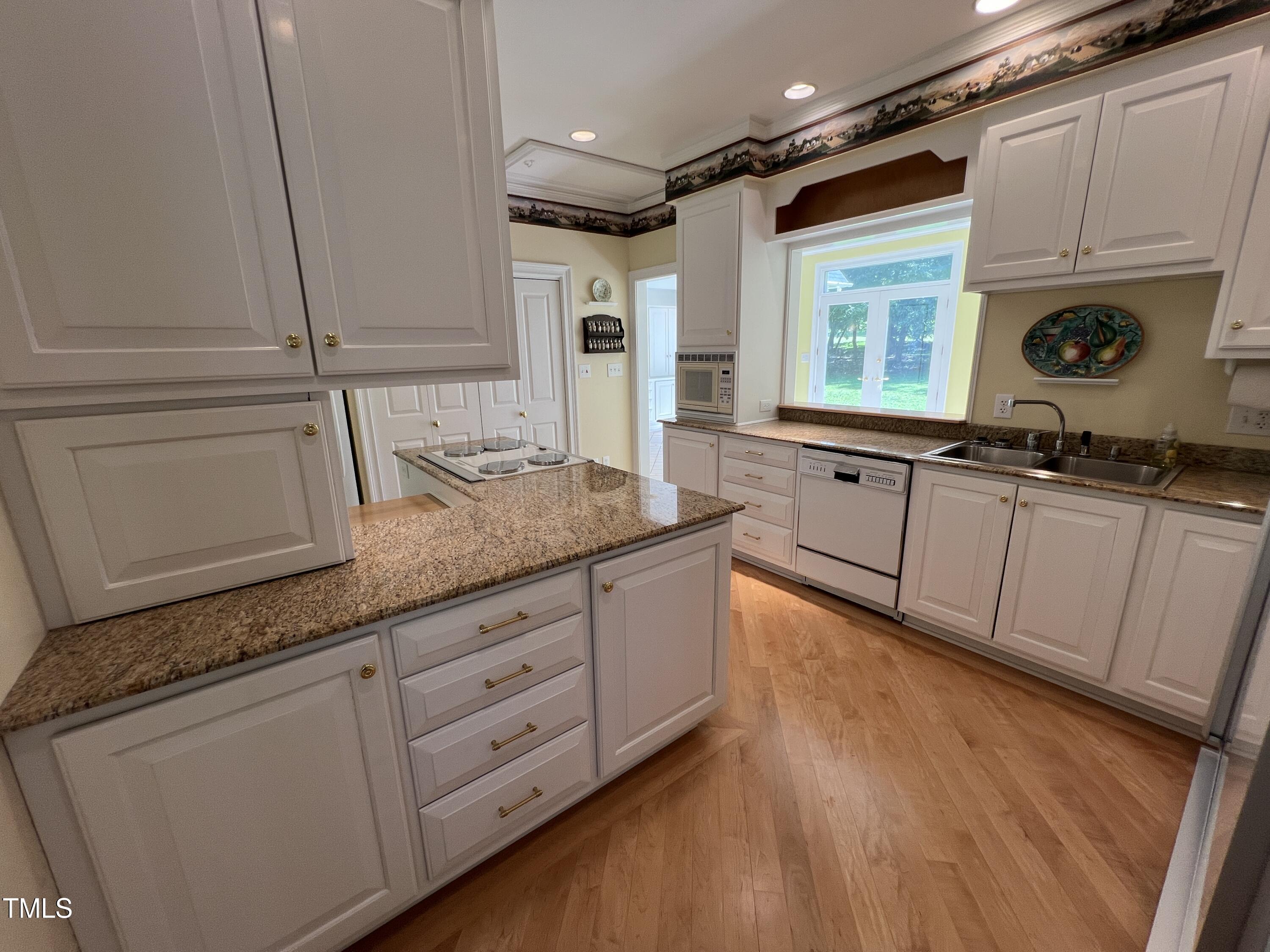 1208 Goodwin Road Apex, NC 27523 - Photo 23 of 42 a kitchen with granite countertop white cabinets and white appliances