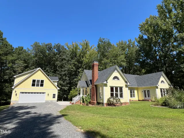 a view of a house with a yard and large trees