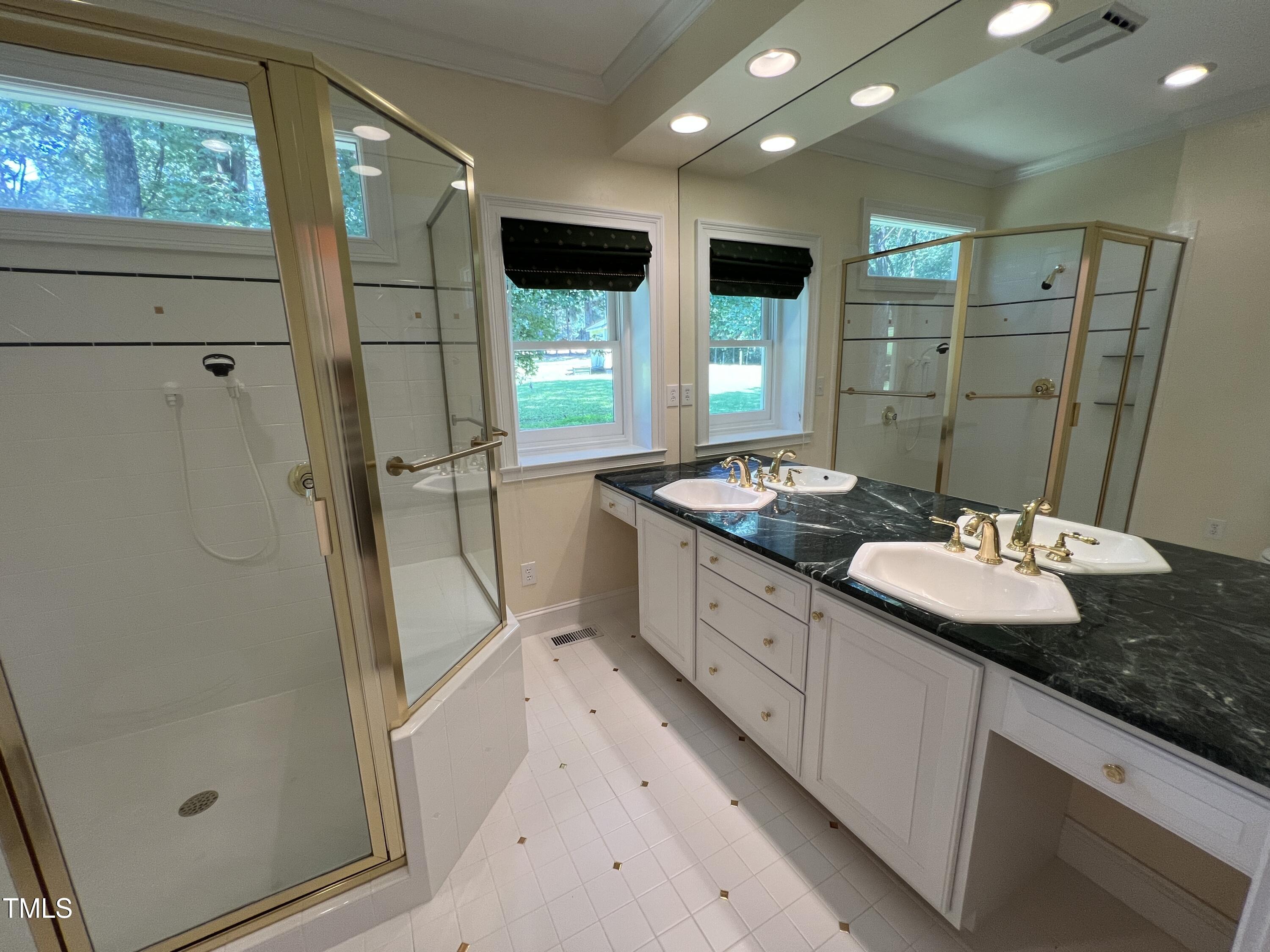 1208 Goodwin Road Apex, NC 27523 - Photo 31 of 42 a bathroom with a granite countertop sink a mirror and shower