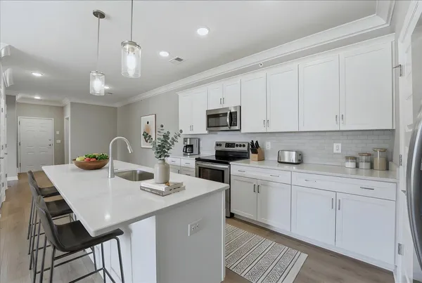 a kitchen with a stove a sink a kitchen island with chairs and cabinets