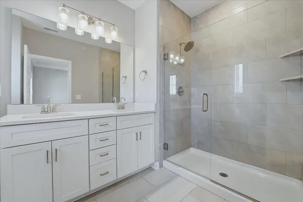 a bathroom with a double vanity sink mirror and shower