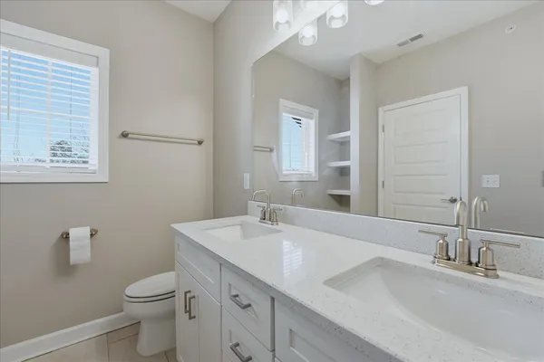 a bathroom with a granite countertop toilet sink and mirror