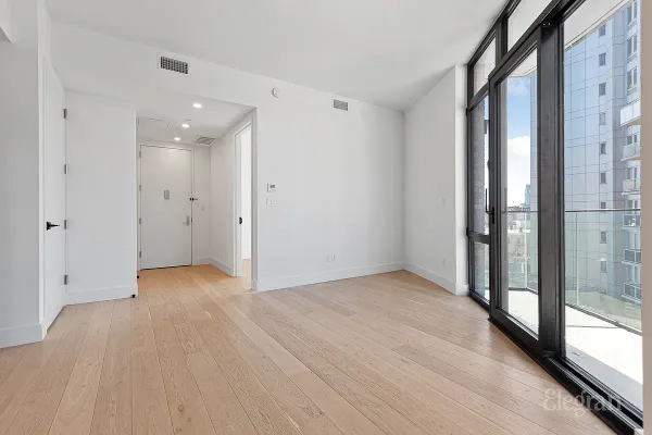 a view of an empty room with a window and wooden floor