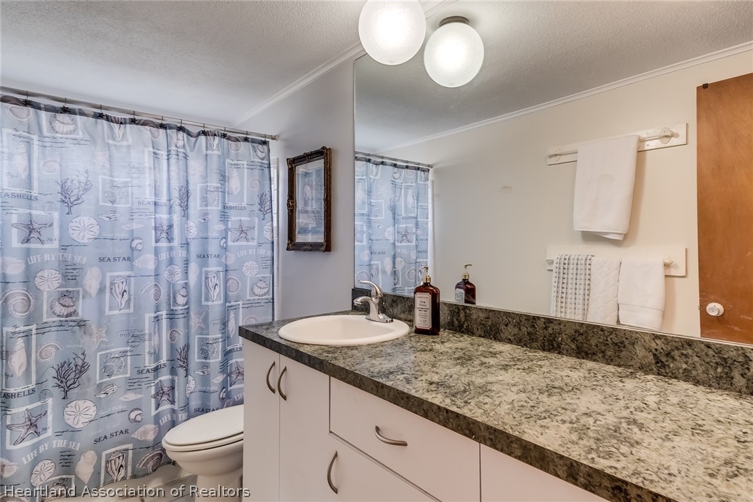 3264 Golfview Road Sebring, FL 33875 - Photo 13 of 27 a bathroom with a granite countertop sink a toilet and a mirror