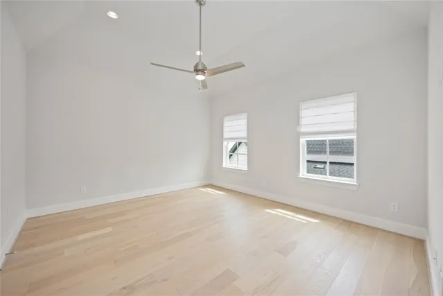 an empty room with a window and ceiling fan