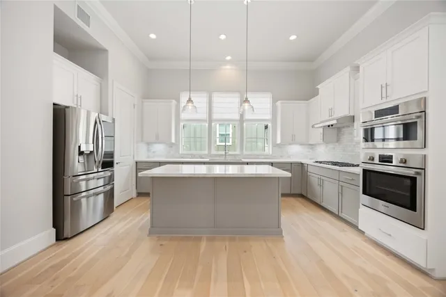 a large kitchen with stainless steel appliances a large counter top a stove a sink and a refrigerator