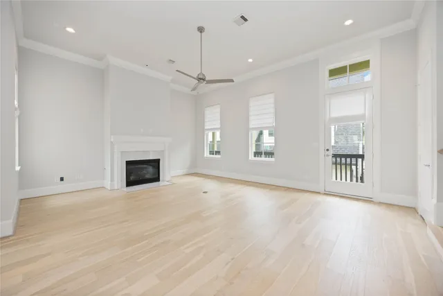 an empty room with wooden floor fireplace and windows